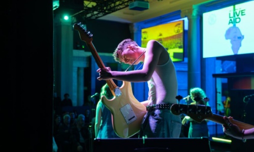 Guitarist performing on stage with a band.